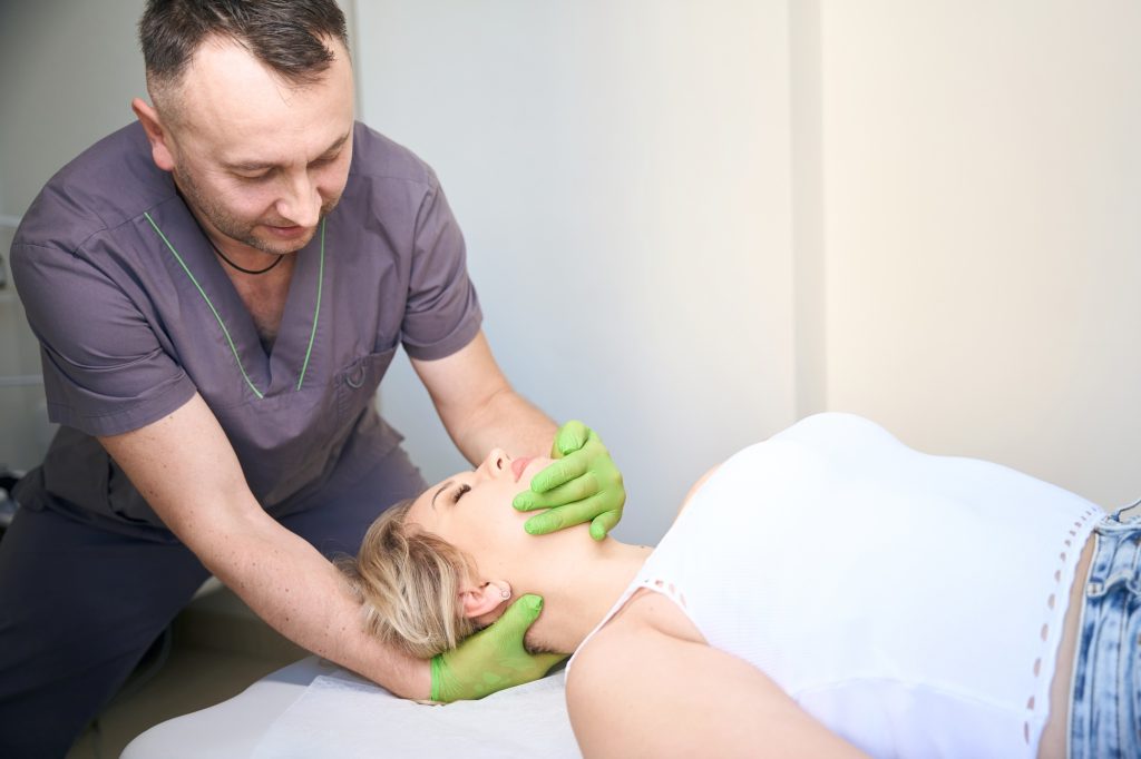 Osteopathic physician carrying out cranial osteopathy on adult female
